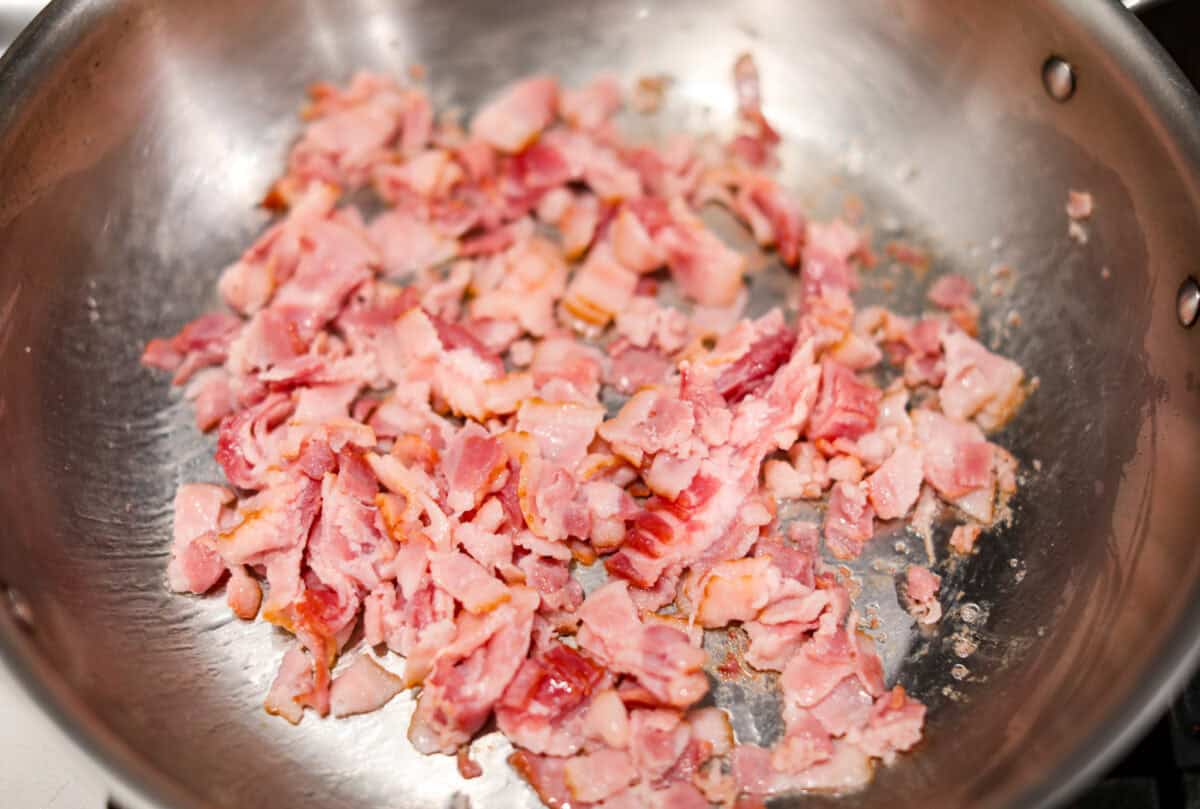 Overhead shot of bacon being cooked in a skillet. 