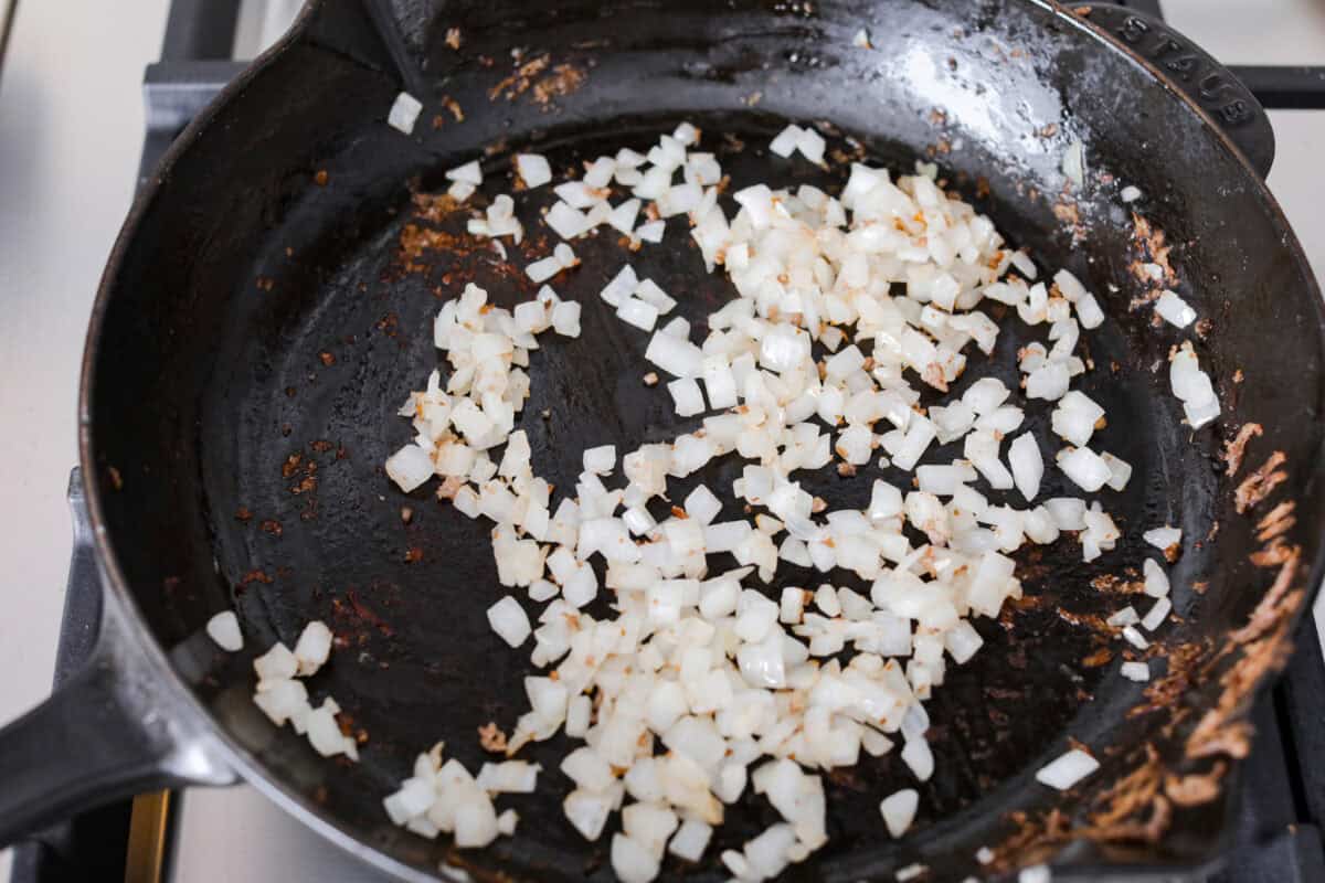 Overhead shot of onions  being sautéed in a skillet. 