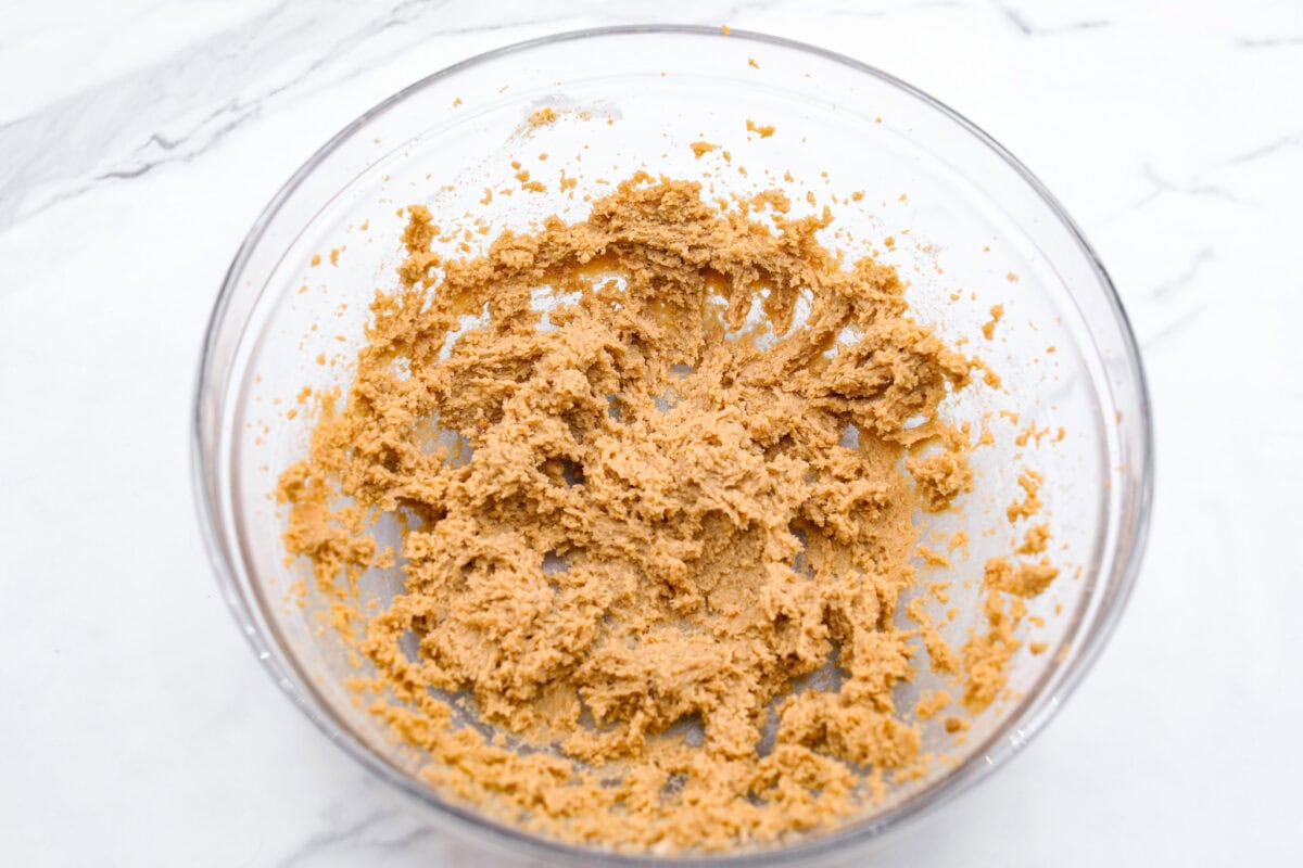 Overhead shot of butter and sugars mixed in a glass bowl. 