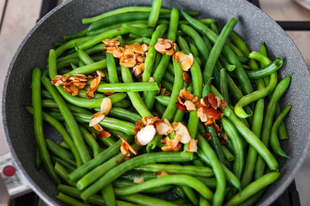 Overhead shot of steamed green beans with the almond, butter and lemon juice poured over the top. 