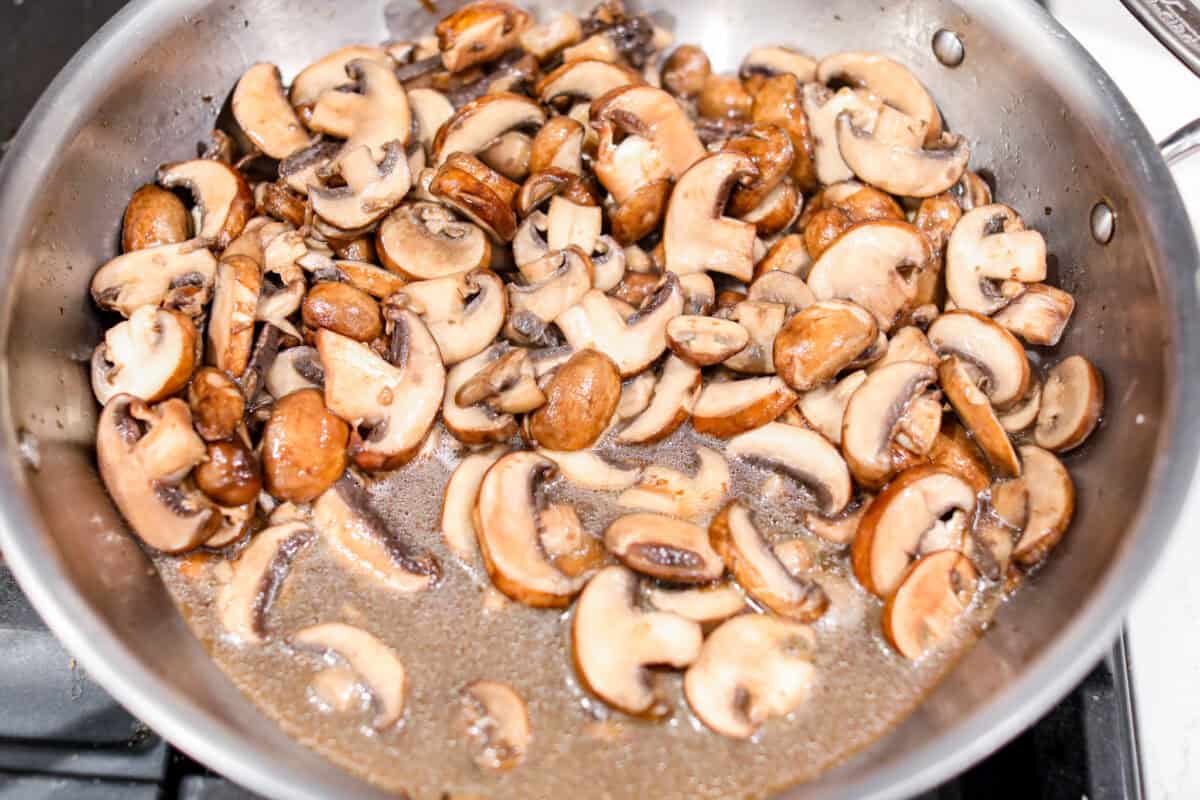 First photo of mushrooms cooking in a large skillet.