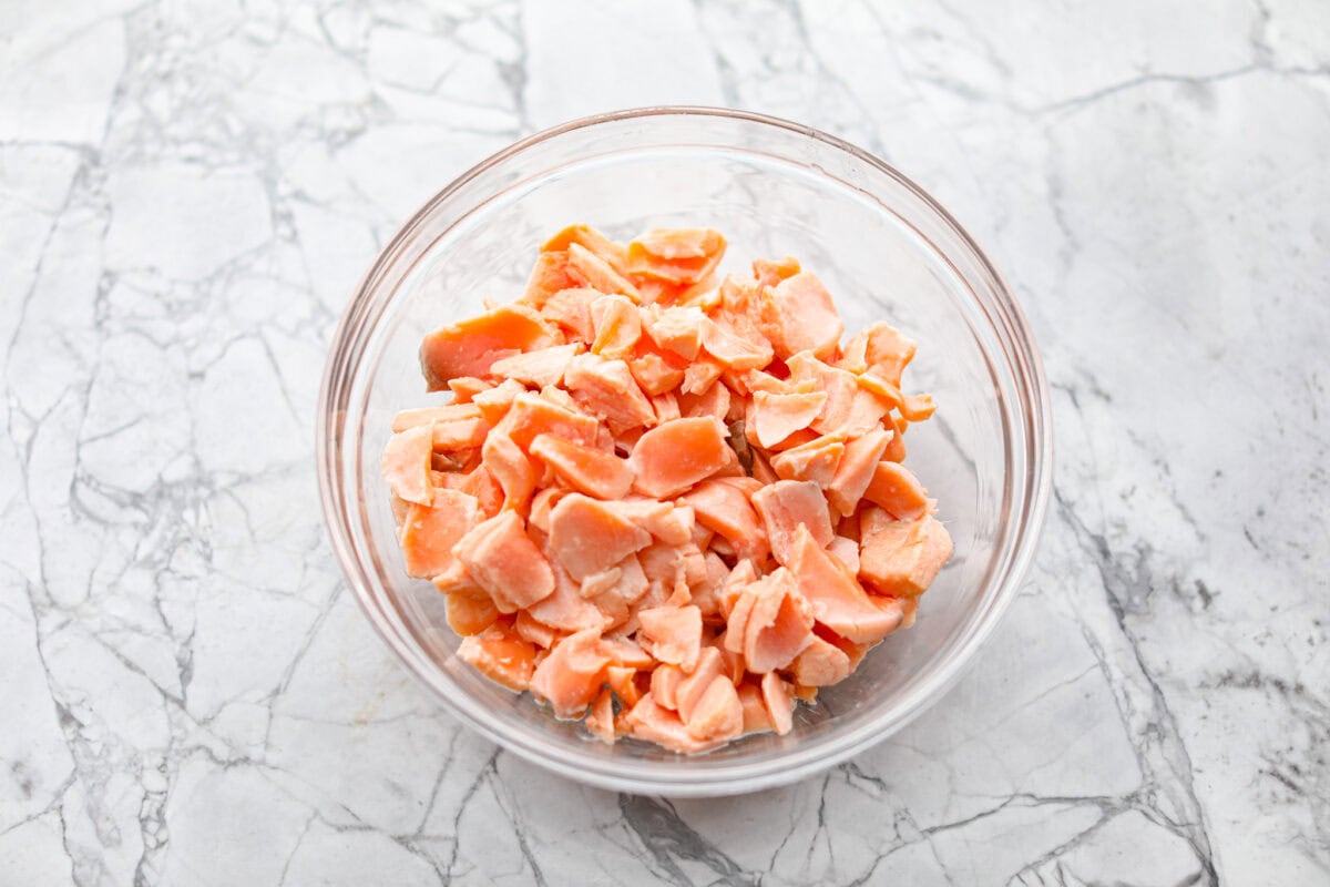 Overhead shot of flaked salmon in a glass bowl. 