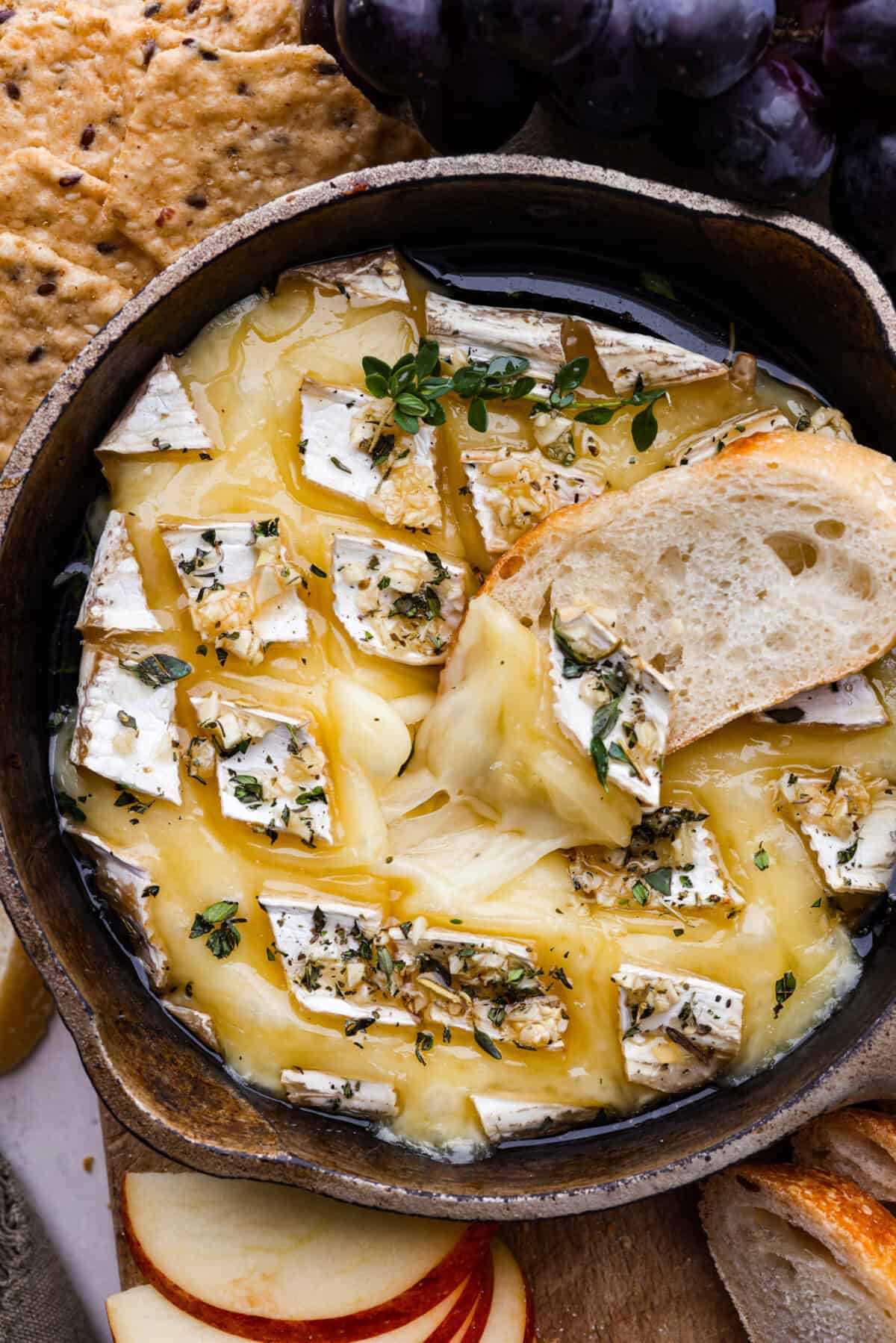 Overhead shot of melty baked brie in a skillet with pice of bread in it. 