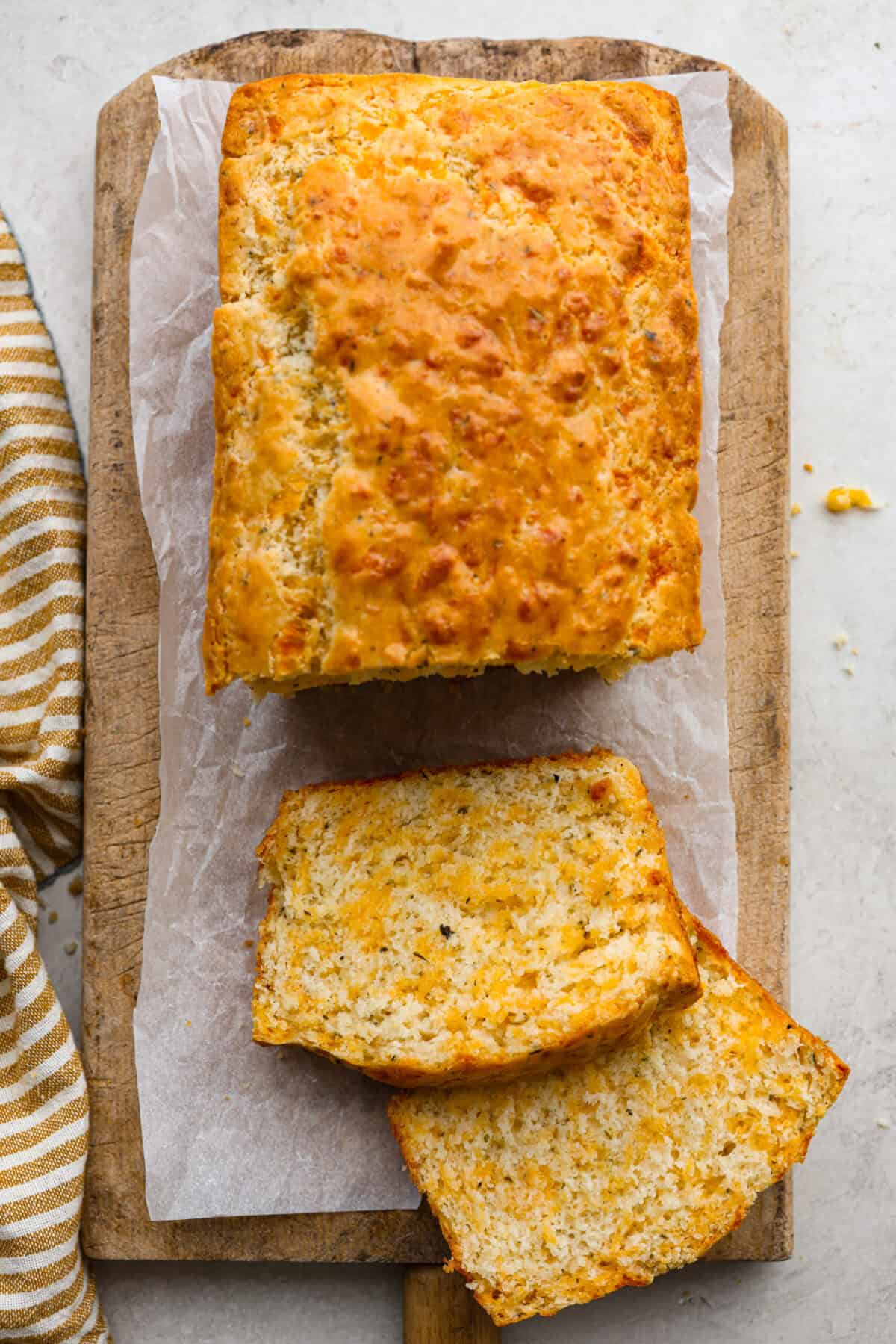 Overhead shot of loaf of cheesy quick bread with a couple pieces cute from it. 