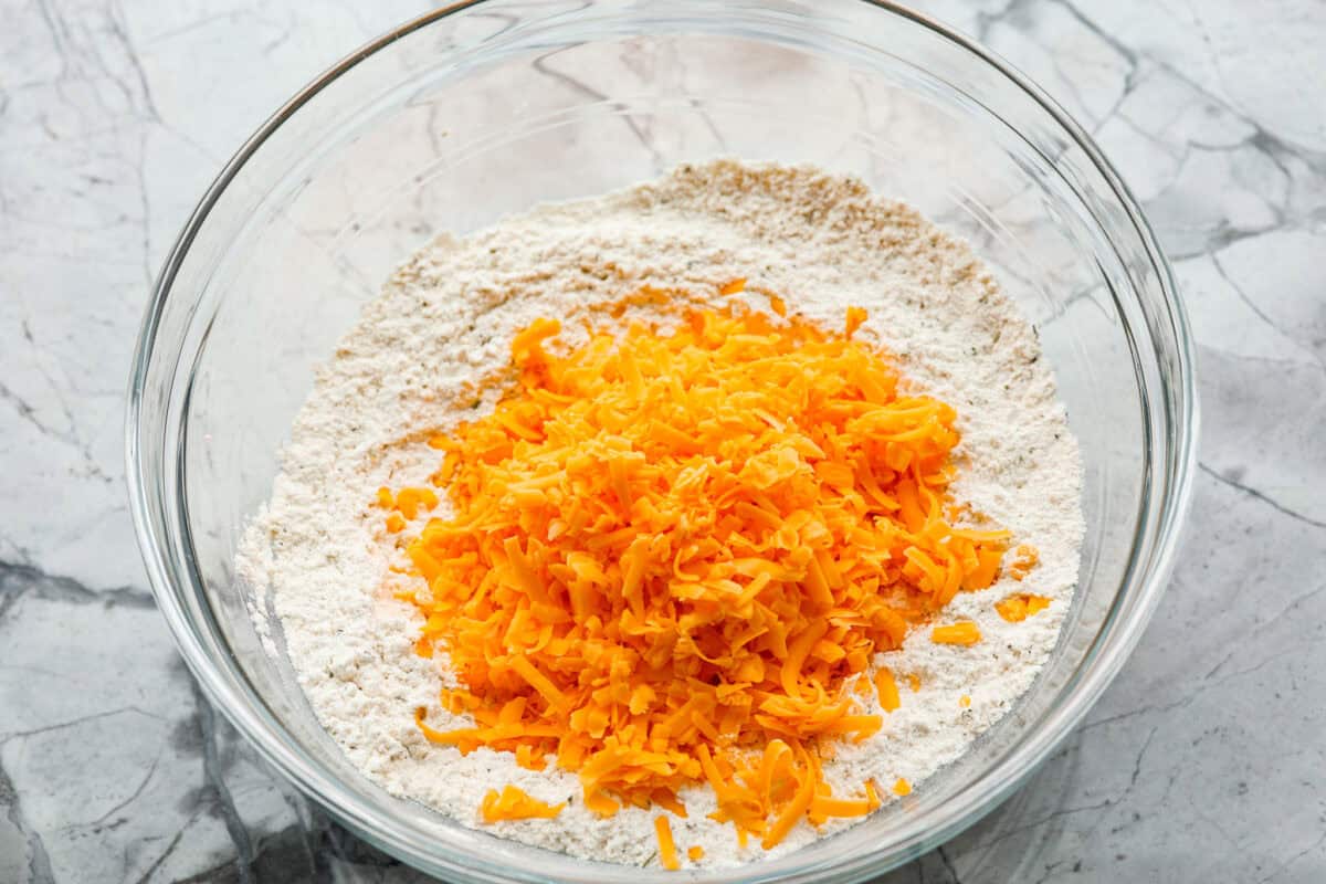 Overhead shot of cheese added to the dry ingredients. 