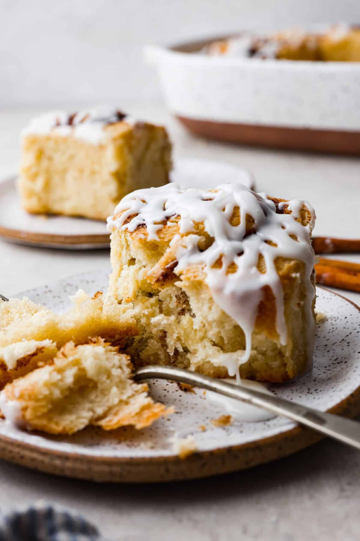 side shot of a plated biscuit cinnamon  roll cut with a fork. 