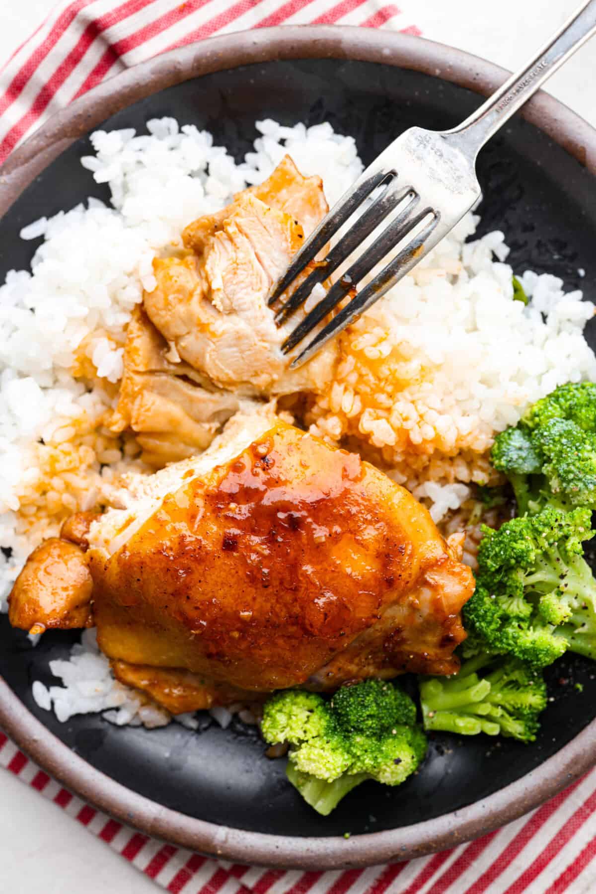 Overhead shot of plated coca-cola chicken thighs over rice and brocolli. 