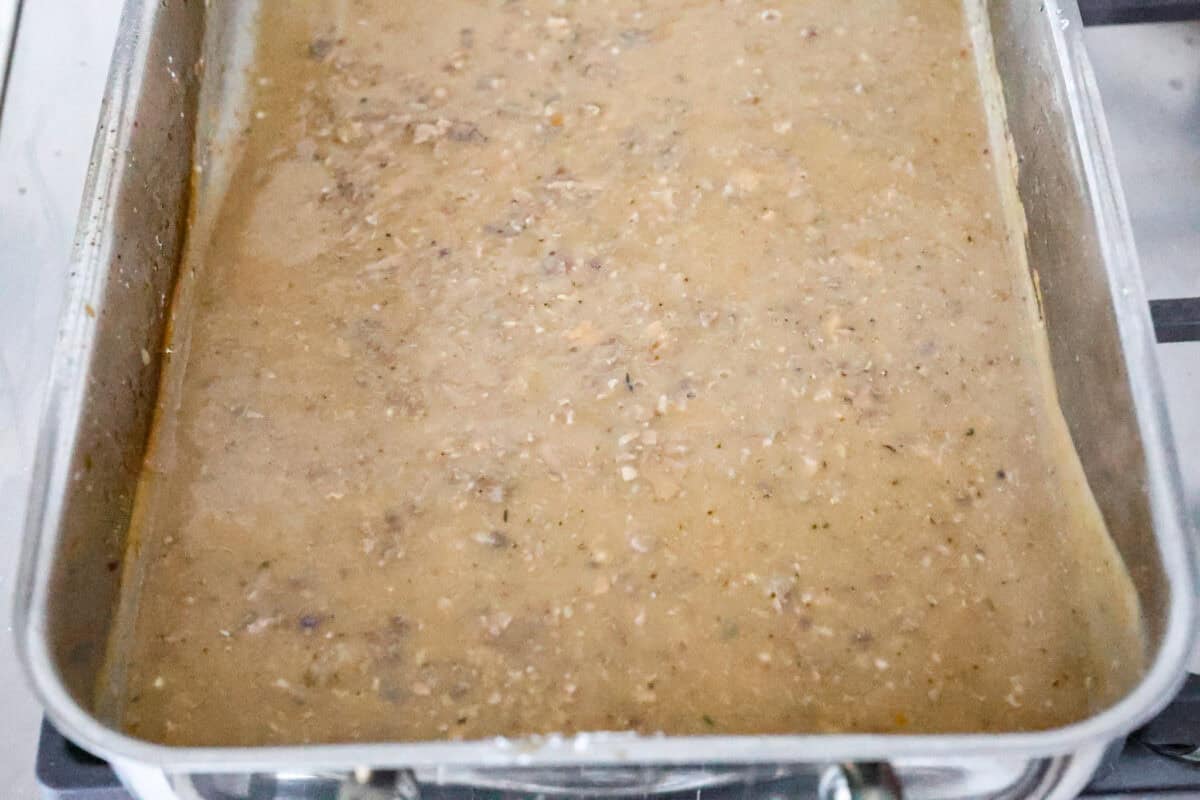 Overhead shot of giblet gravy being heated up in the turkey pan. 