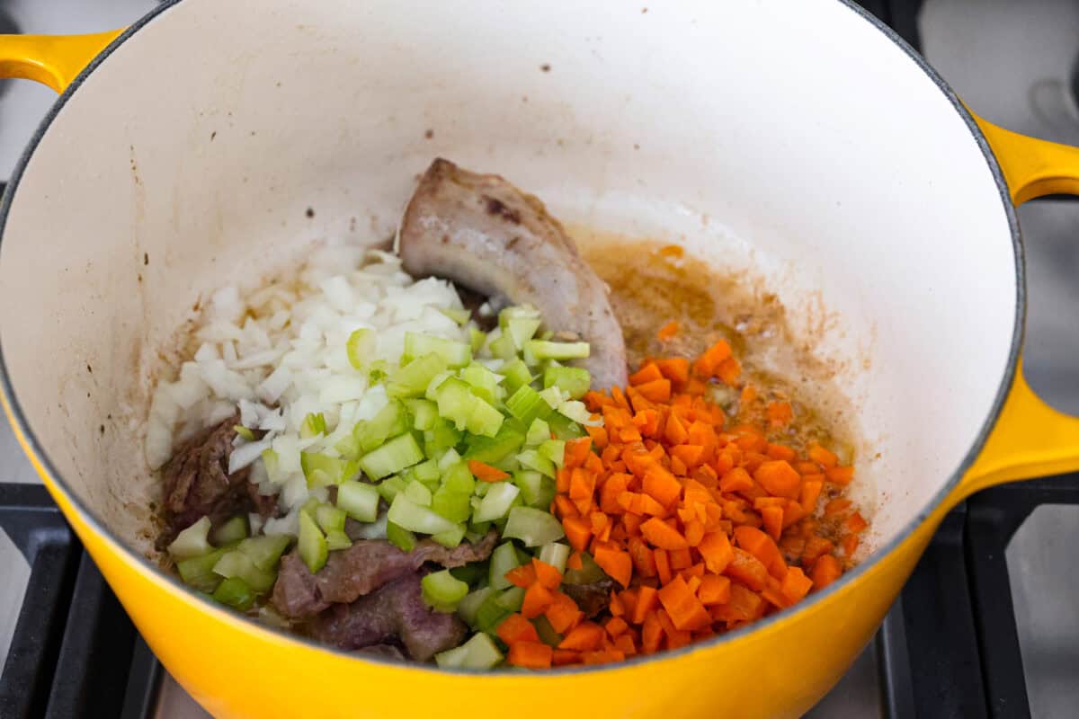 Angle shot of celery, carrots and onions in the pot with cooking giblets. 