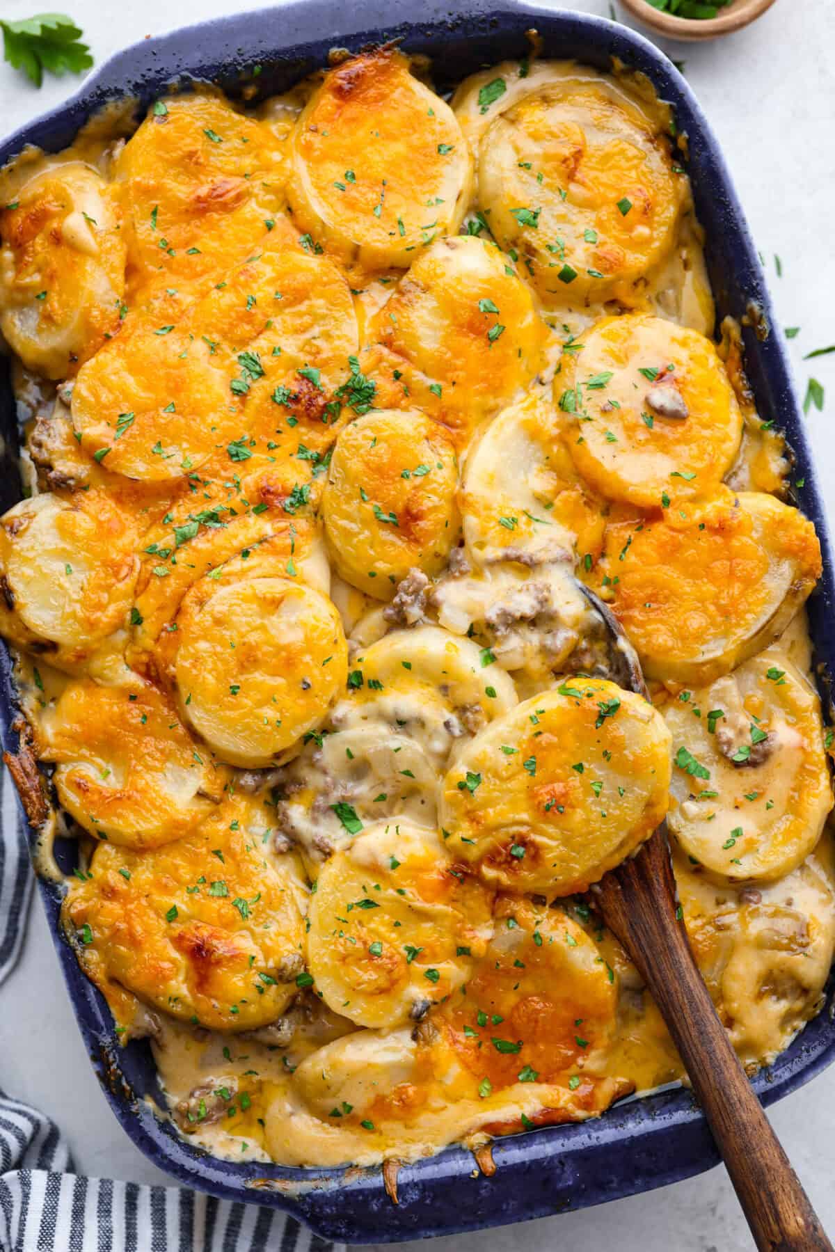 Overhead shot of hamburger potato casserole with wooden serving spoon. 