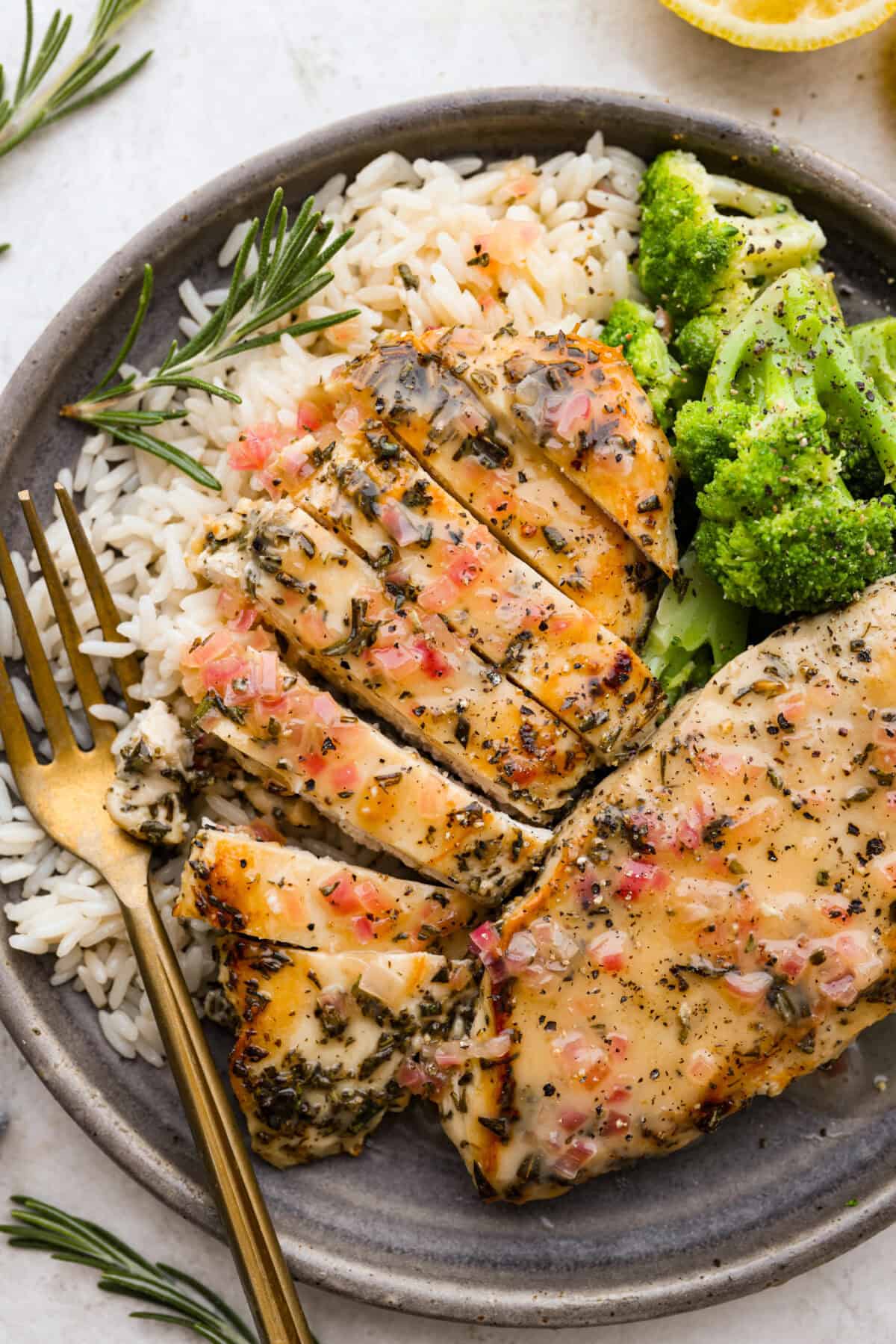 Overhead shot of plated rosemary chicken on a plate with rice and broccoli. 