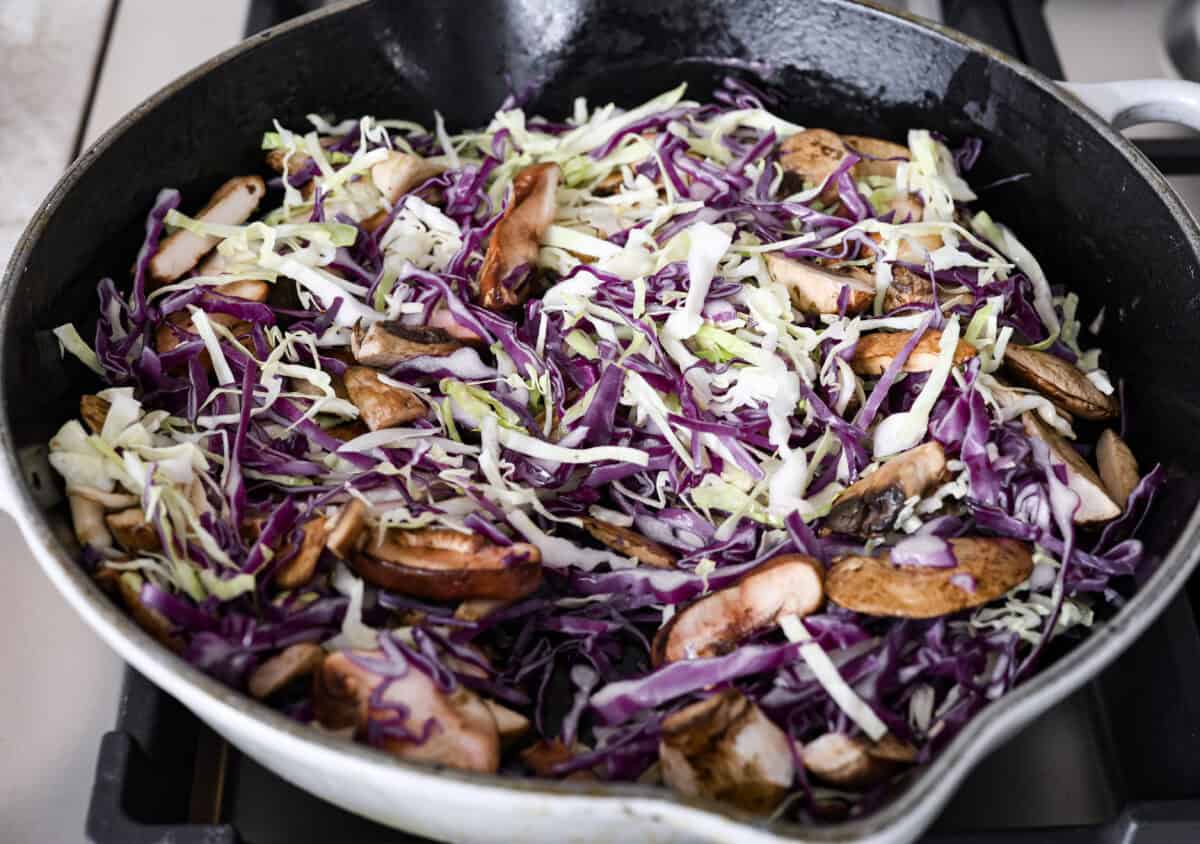 Angle shot of cabbage and mushrooms in a skillet. 