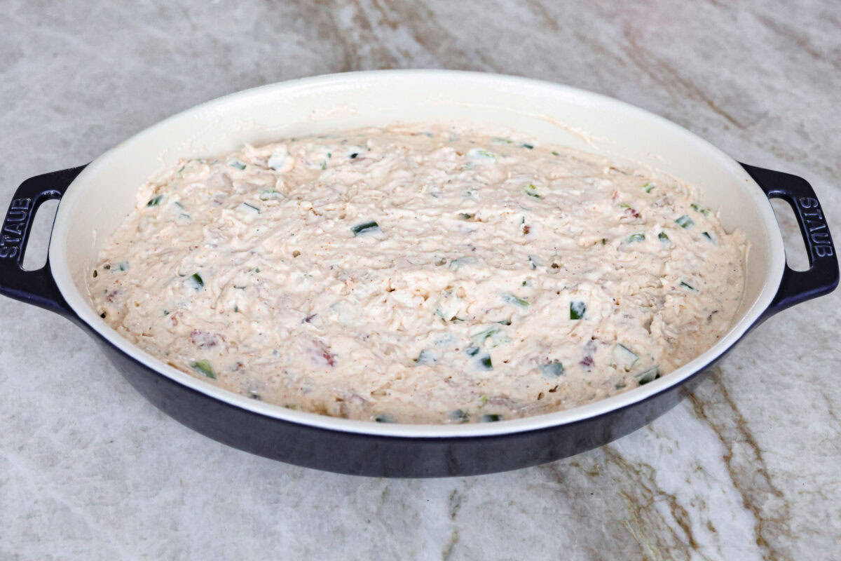 Angle shot of the chicken and cream cheese mixture spread into the bottom of a baking dish. 