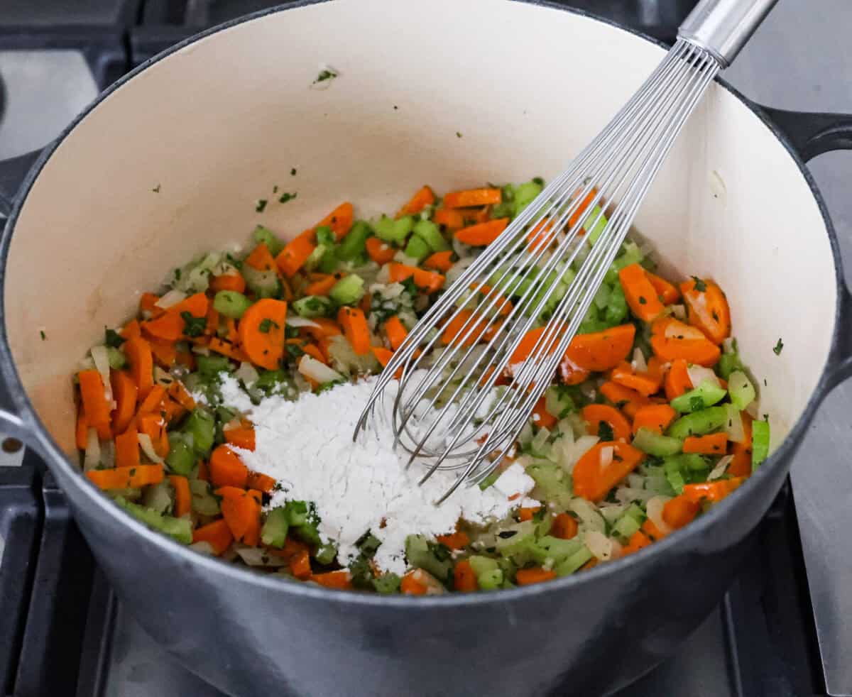 Angle shot of cooked vegetables with butter and flour being whisked in. 