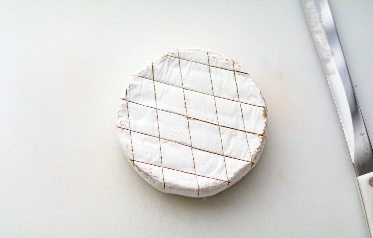 Overhead shot of a circle of brie cheese with diamond slices in the top.