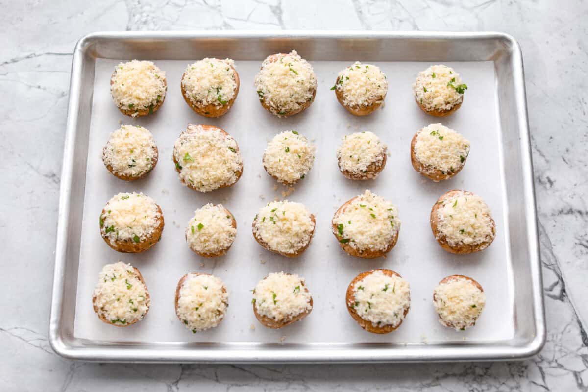 Overhead shot of evenly spaced mushrooms on a cookie sheet. 