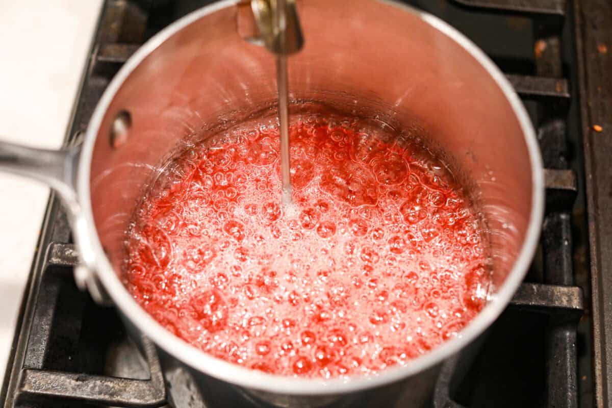 Angle shot of sugars boiling in the saucepan with a candy thermometer sticking out. 