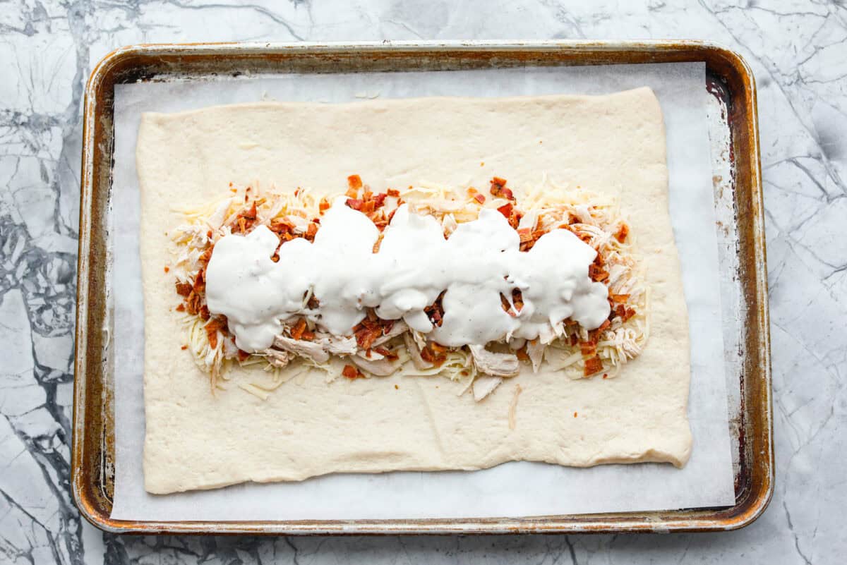 Overhead shot of chicken bacon and ranch spread over the mozzarella. 