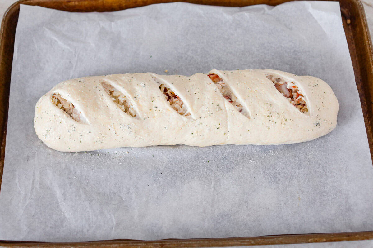 Angle shot of the Stromboli covered and cut  and ready to go in the oven. 