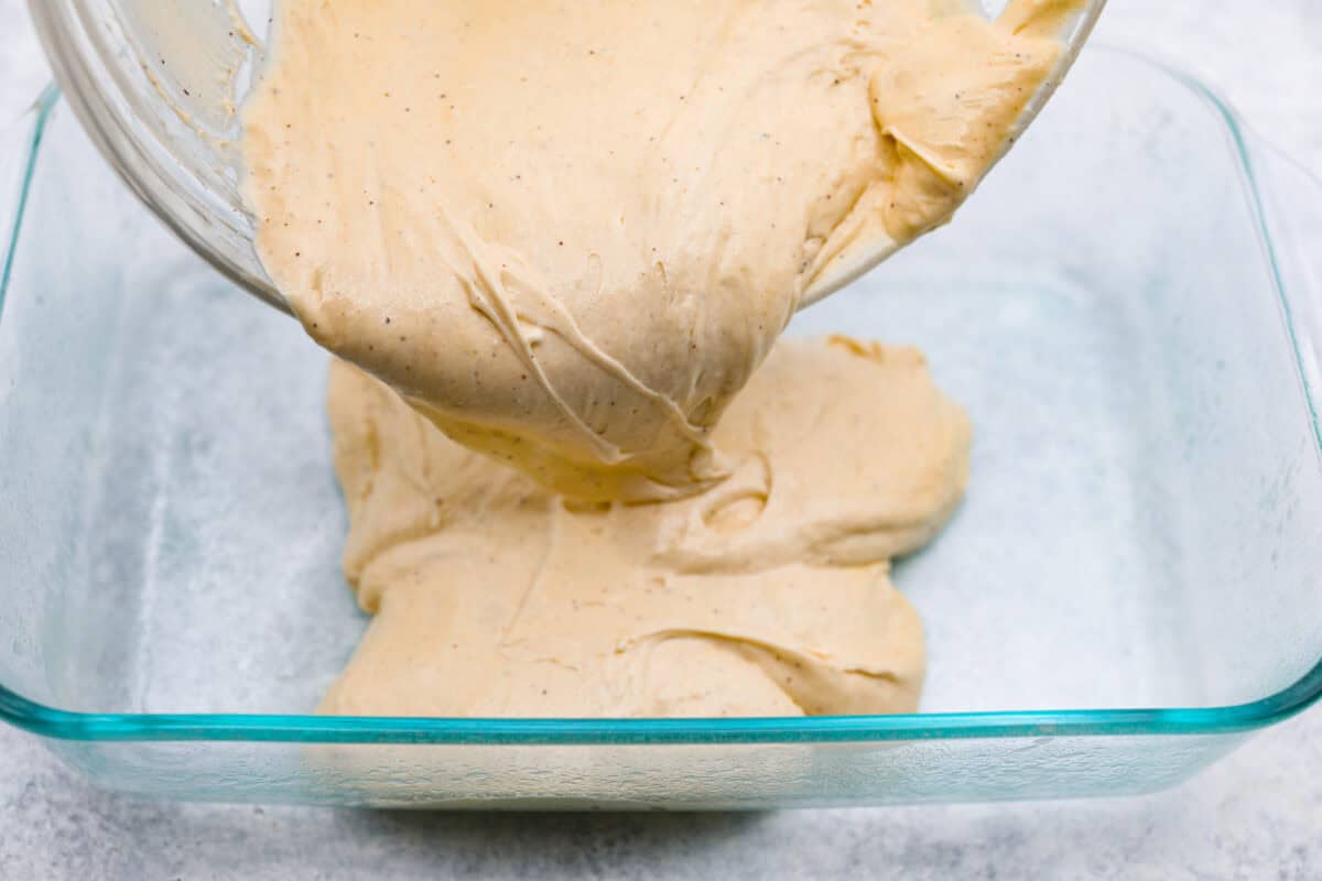 Angle shot of someone pouring the cake batter into a prepared baking dish. 