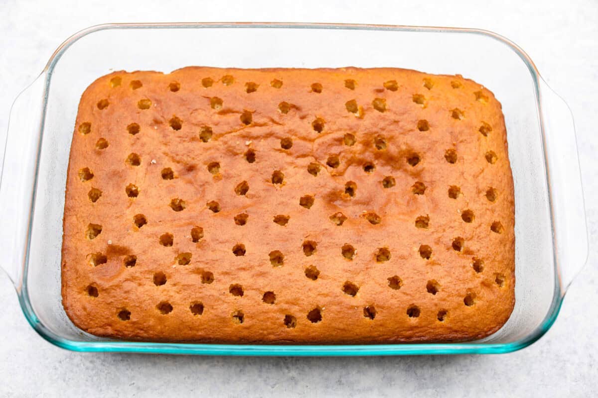 Overhead shot of the baked cake with holes poked in it. 