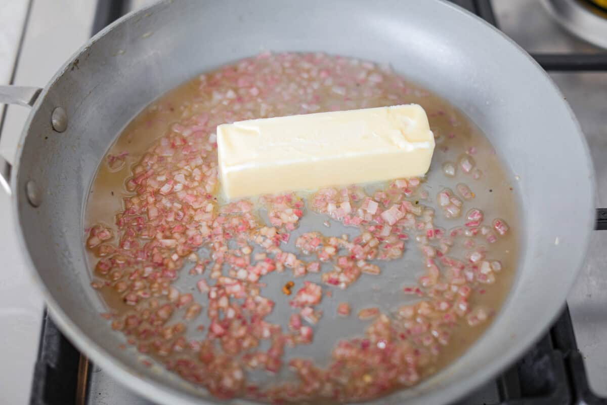 Overhead shot of shallots and juice with oil and butter.