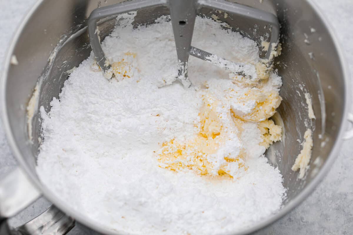 Overhead shot of powdered sugar dumped in with the butter and cream cheese mixture. 