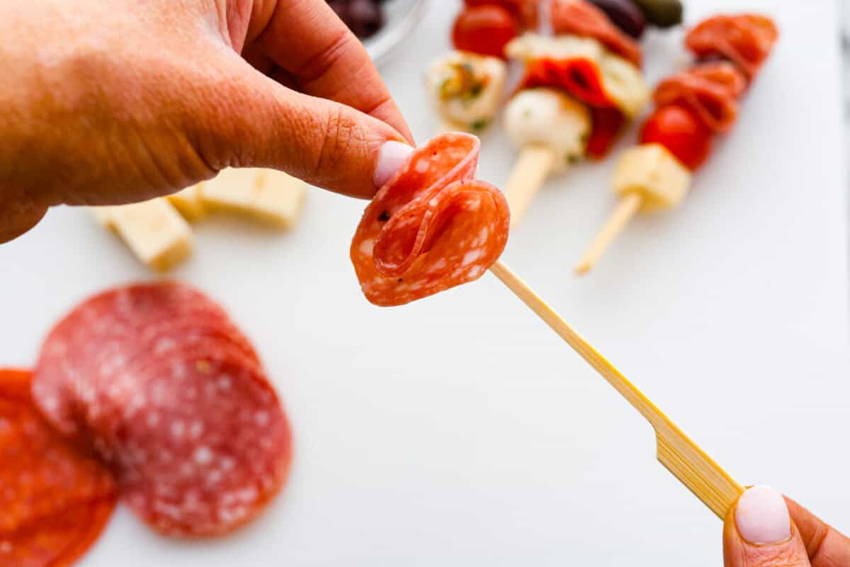 First photo of the pepperoni being placed on a skewer.