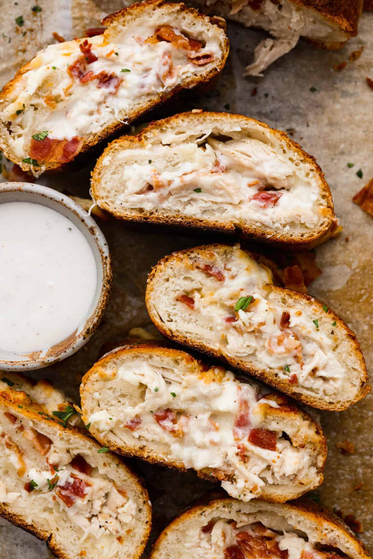 Overhead shot of the chicken bacon ranch Stromboli cut and flipped on its side next to a side of ranch. 