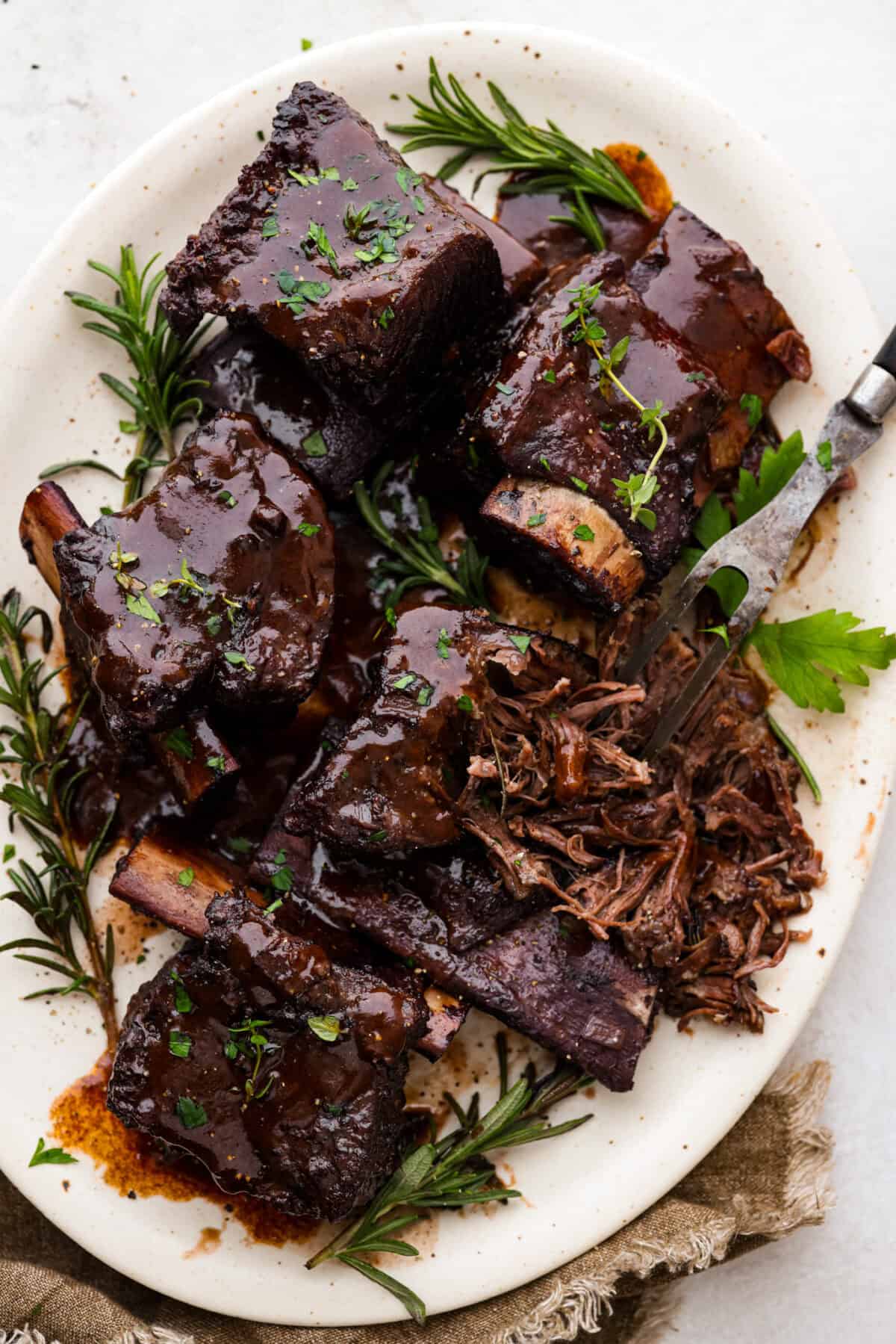 Top view of braised short ribs on a platter with gravy and a serving fork.