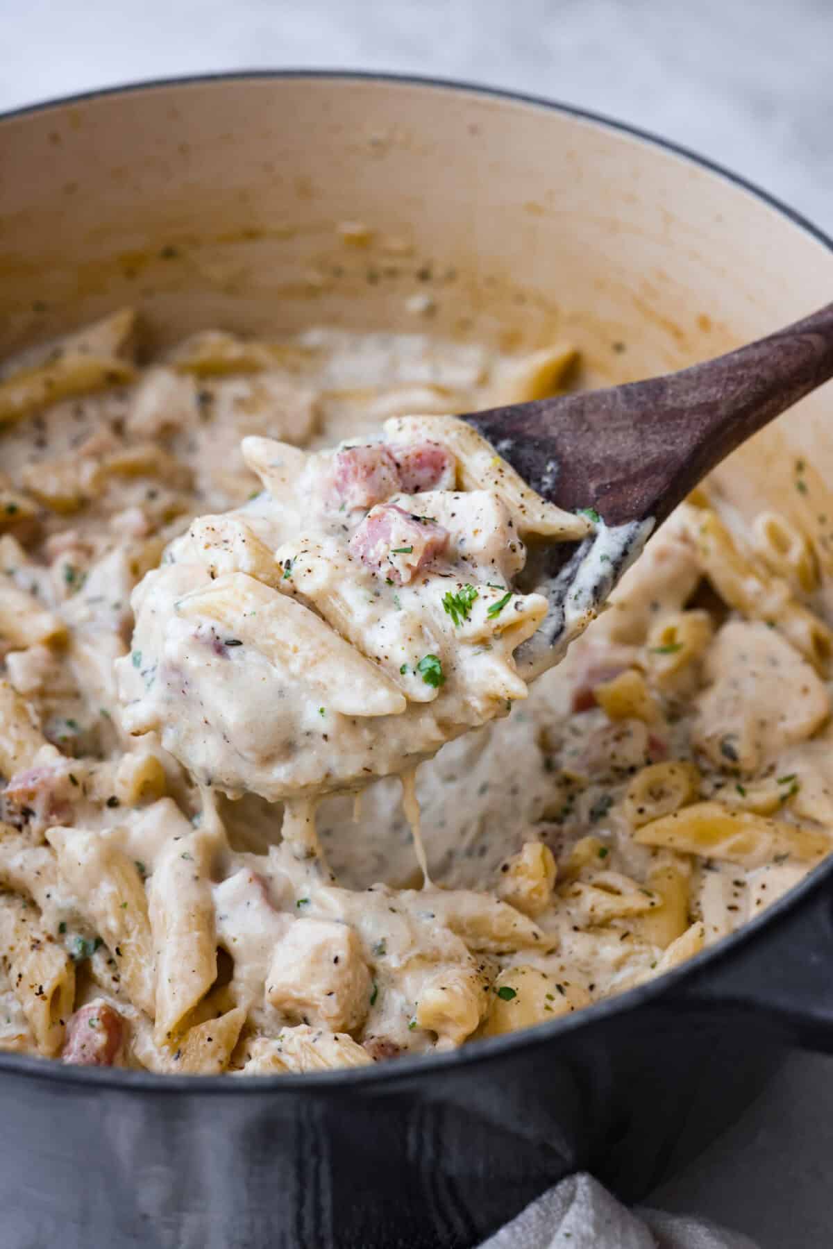 Close up shot of a scoop of chicken cordon bleu in a wooden spoon. 