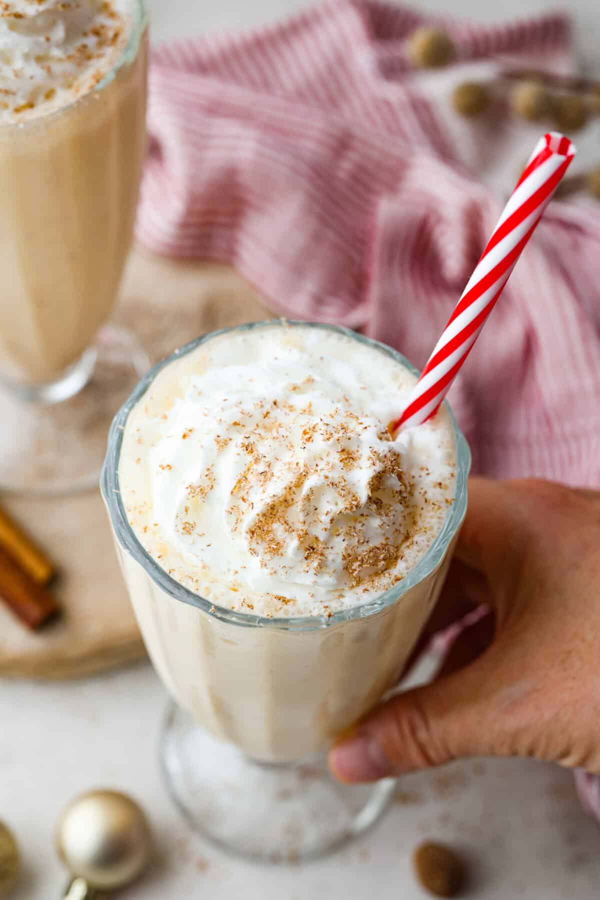 Overhead shot of eggnog milkshake with whipped cream and fresh nutmeg shavings on top.