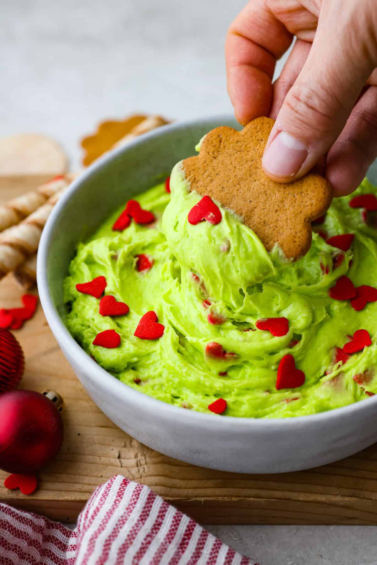 Angle shot of someone dipping a cookie into the Grinch Dip. 