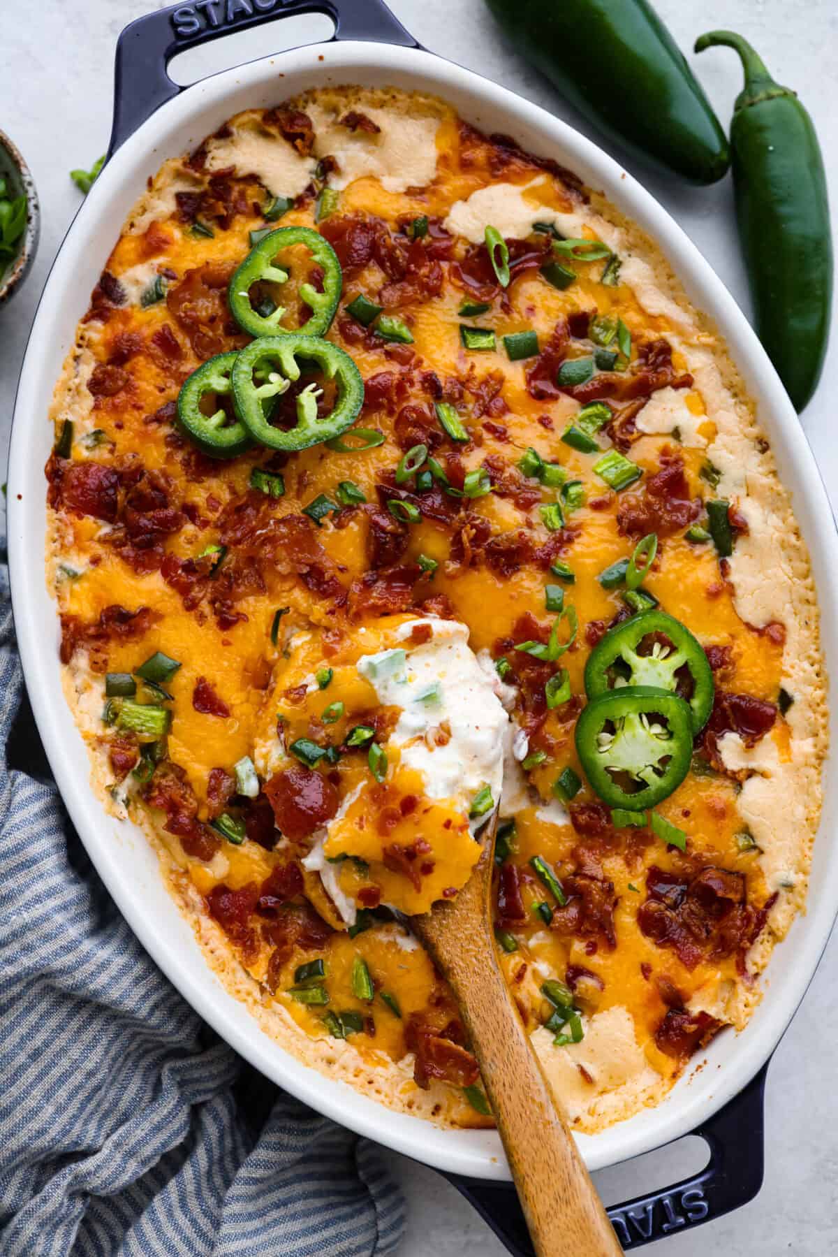 Overhead shot of jalapeño popper casserole in a baking dish with wooden serving spoon. 