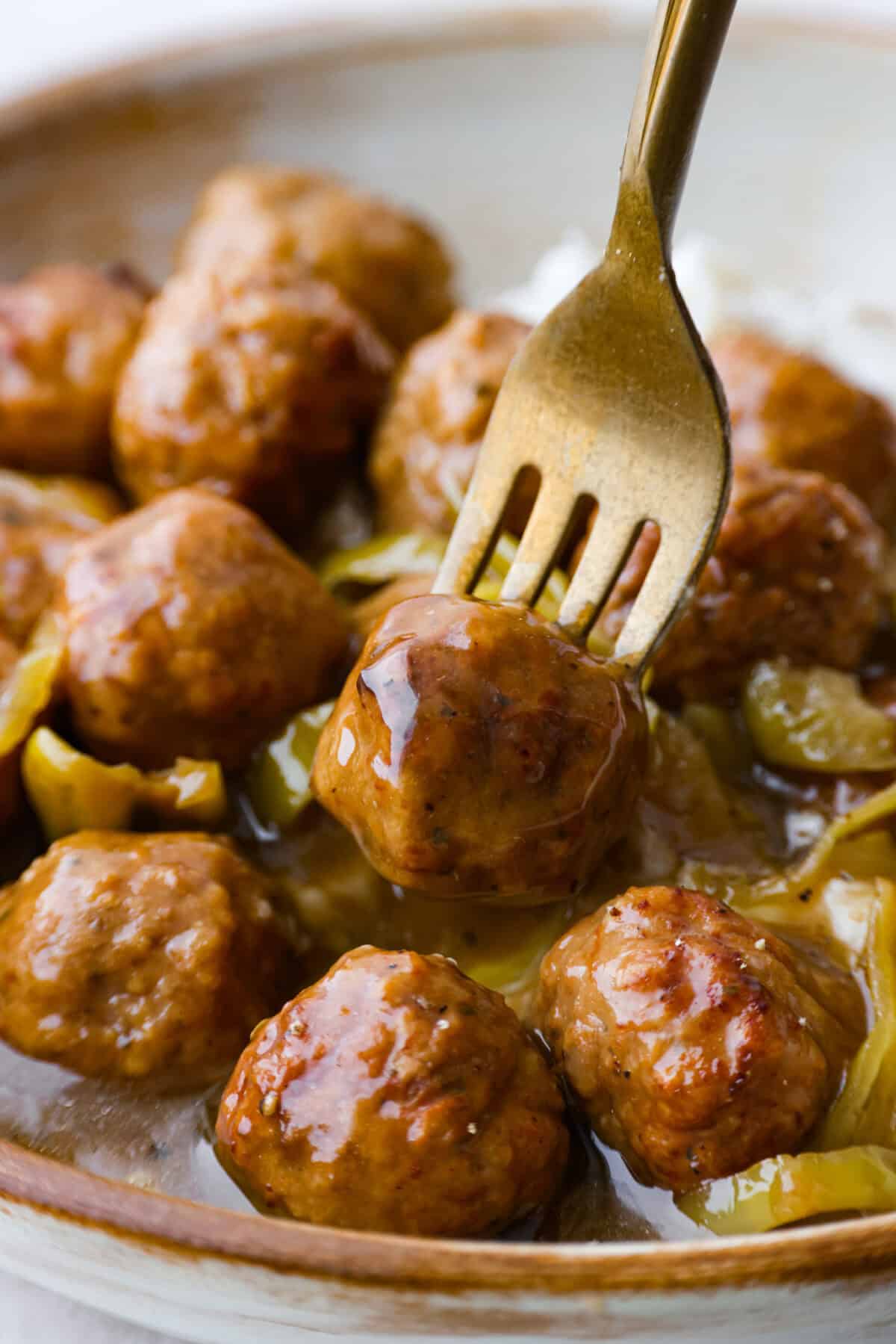 Close up shot of a gold fork with a crockpot Mississippi meatball skewered on the end. 