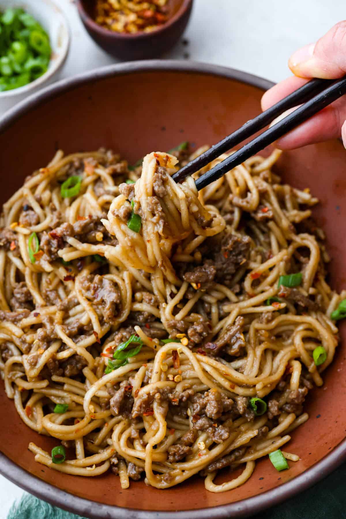 Angle shot of someone getting a bite with Mongolian ground Beef and Noodles. 