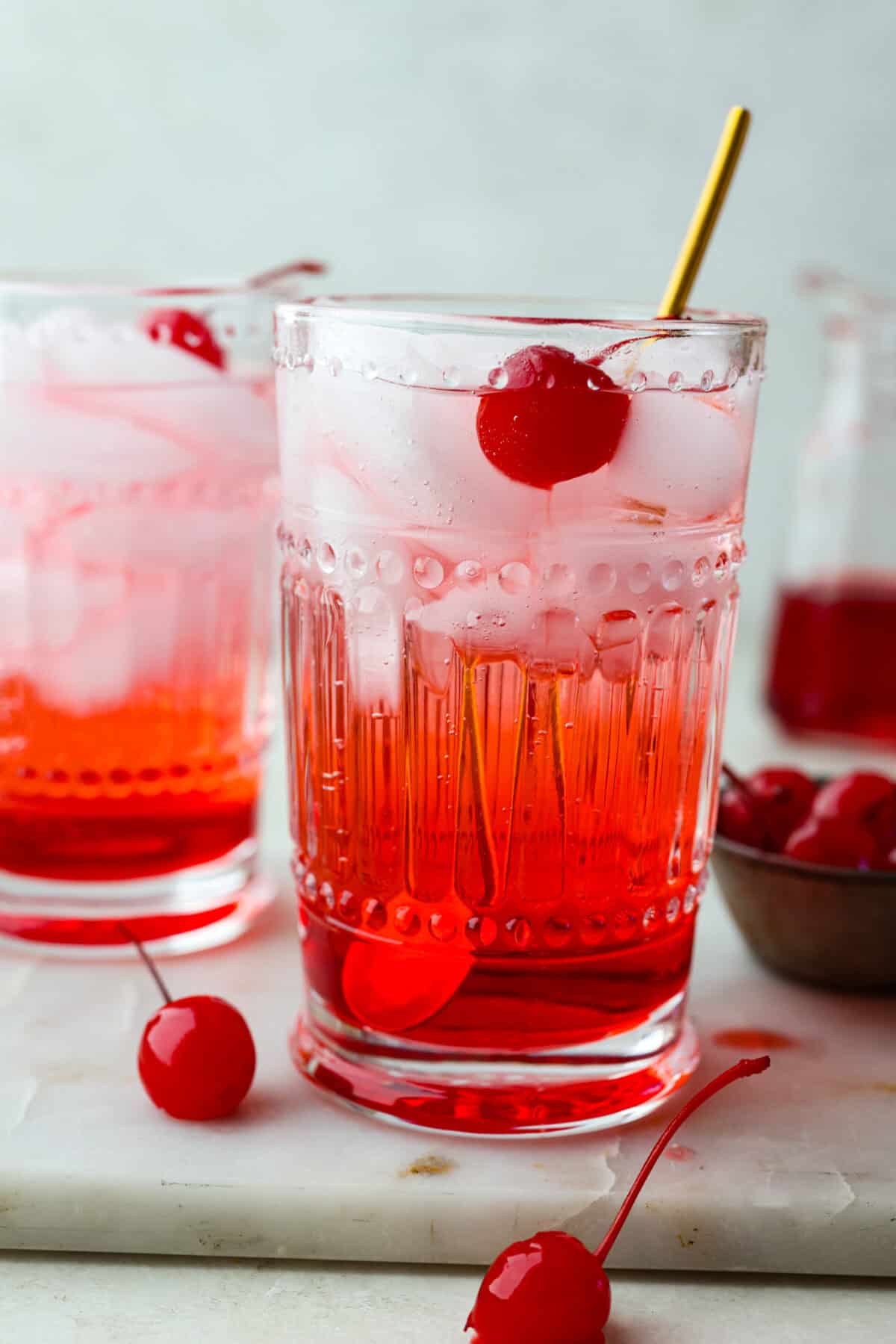 Side shot of Shirley Temple in a glass with maraschino cherry inside. 