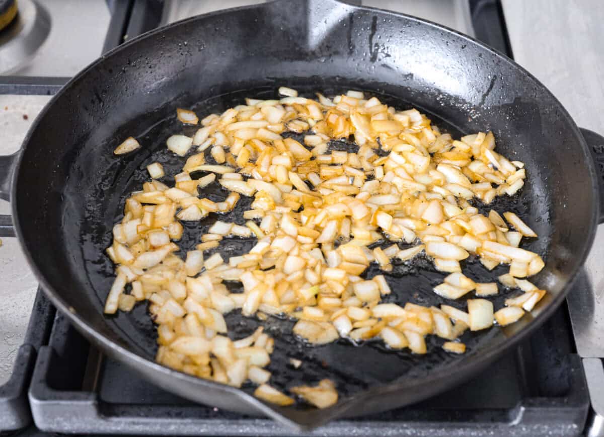 Angle shot of onions cooking in a skillet. 