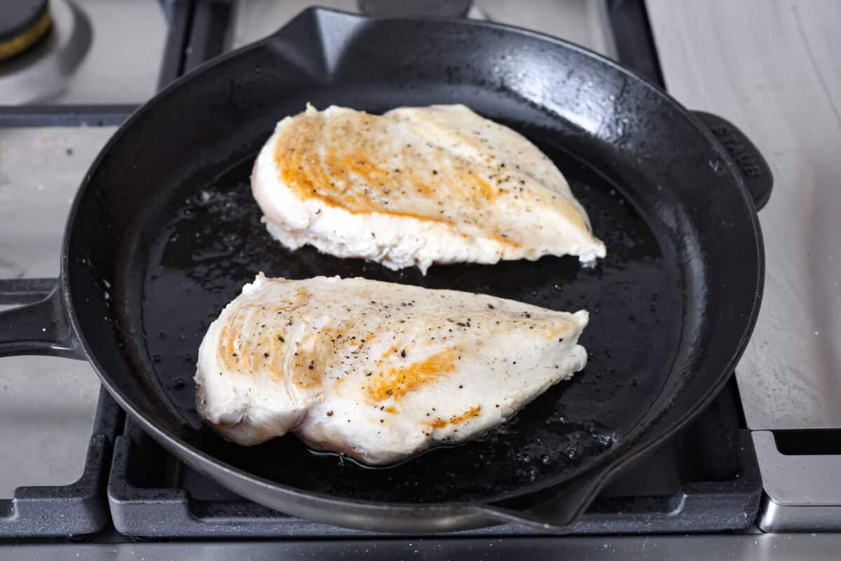 Angle shot of chicken breasts cooking on a skillet. 