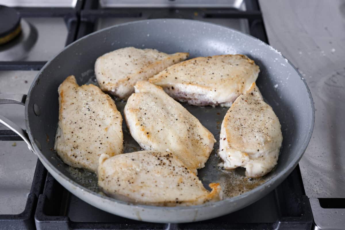 Angle shot of the chicken cooking in a skillet. 