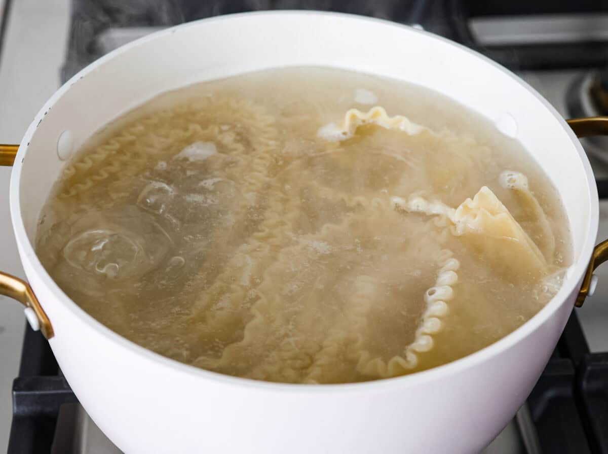 Angle shot of lasagna noodles boiling in a pot of water. 