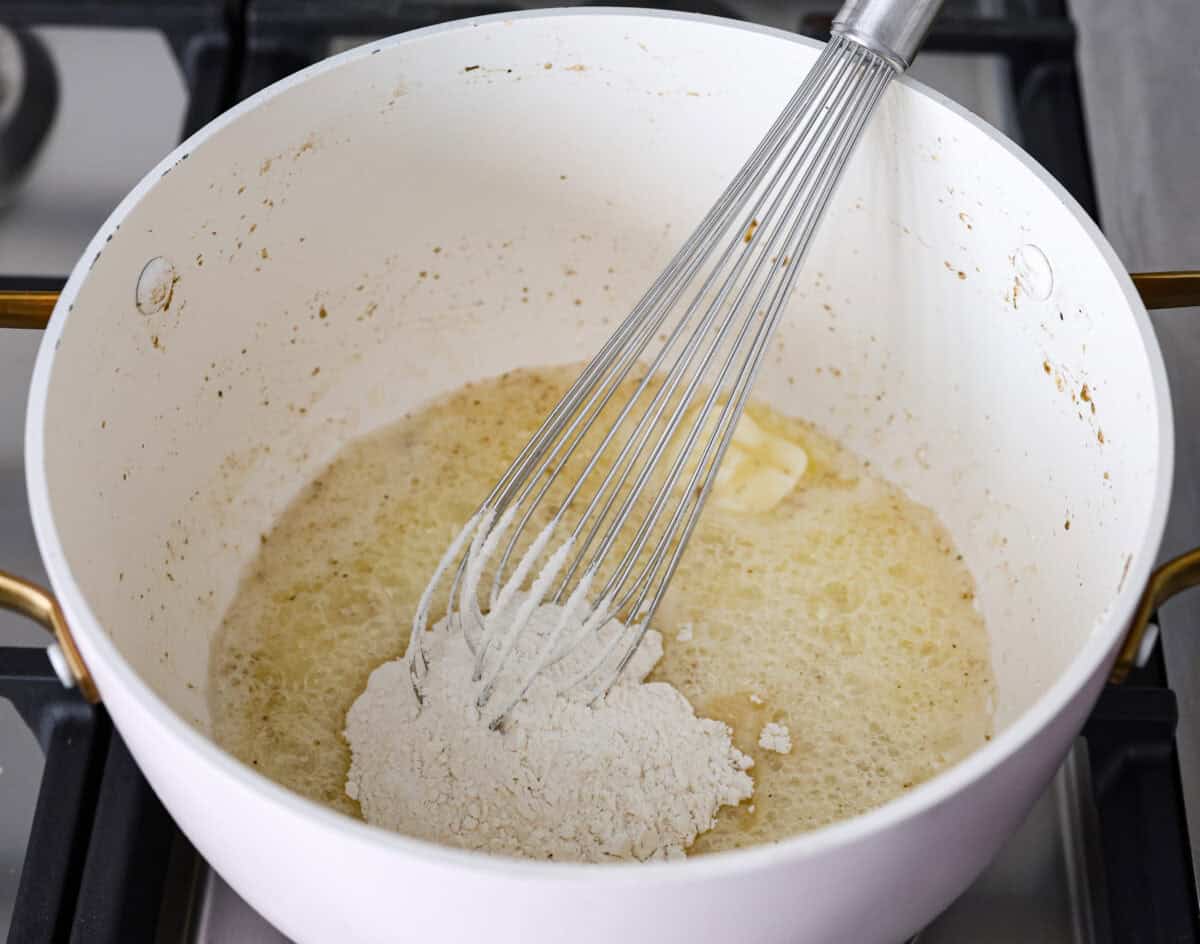 Angle shot of flour being whisked into the melted butter.