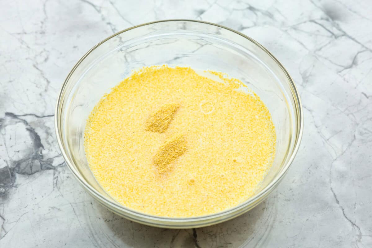 Overhead shot of milk and cornmeal mixed in a bowl. 