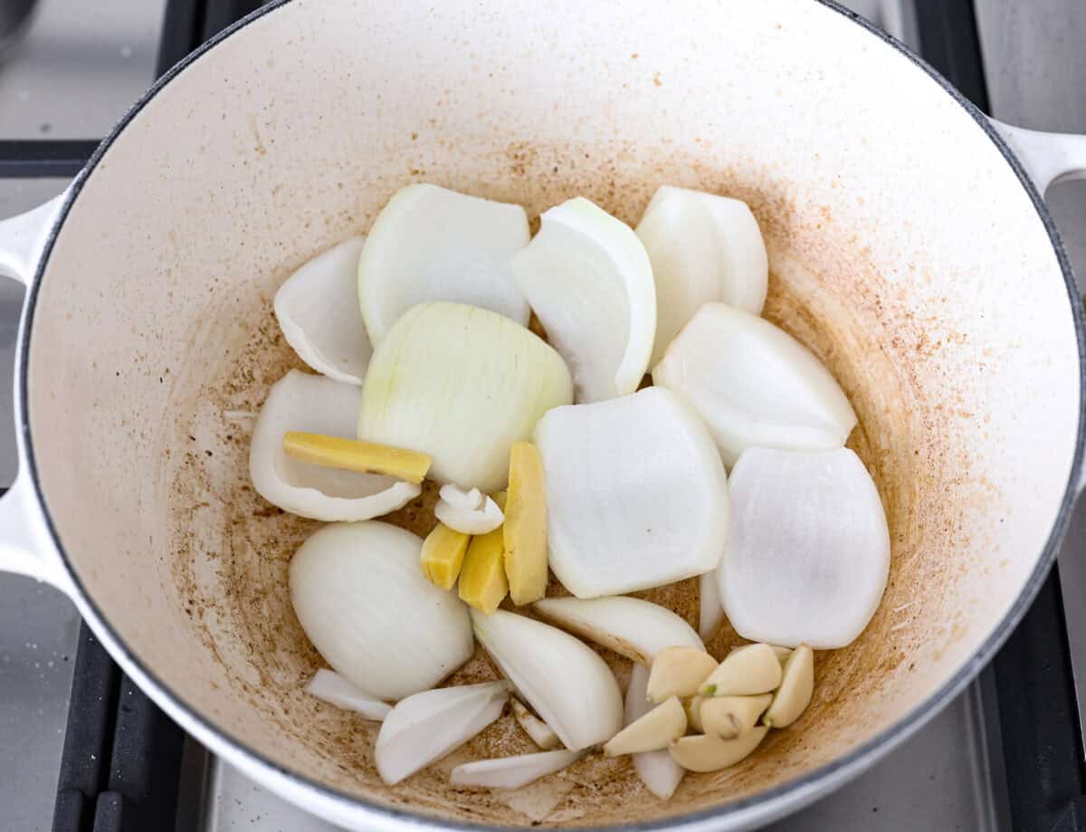 Overhead shot of onions, garlic, ginger, sautéing in a pot. 