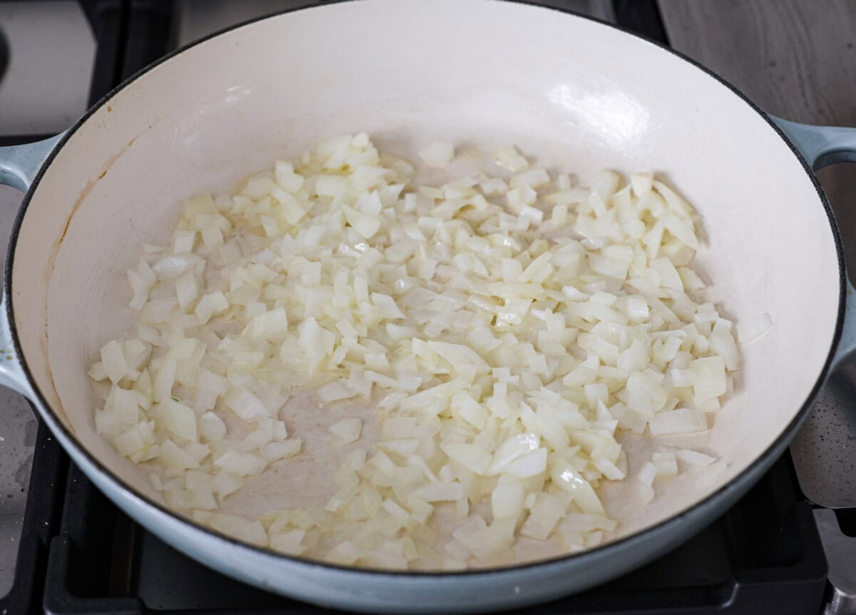 Angle shot of onions sautéing in butter in a skillet. 