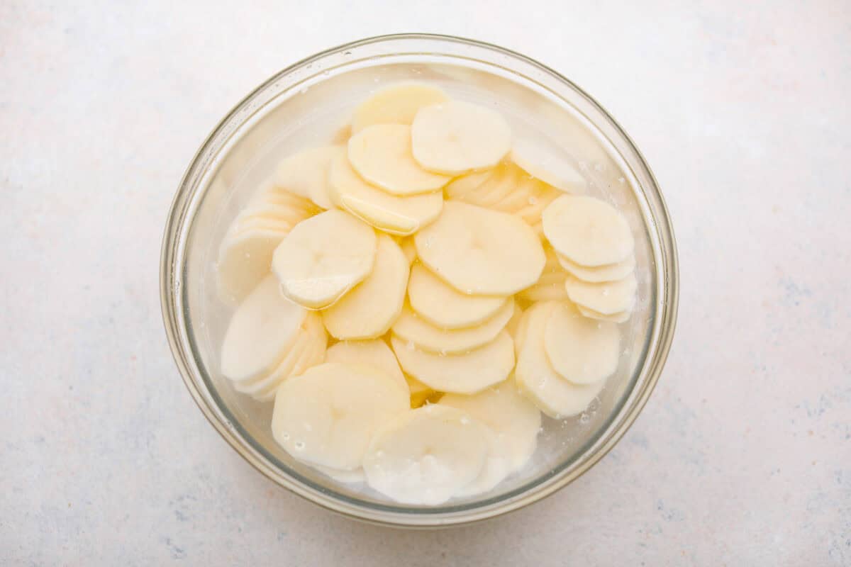 Overhead shot of sliced potatoes in cold water. 