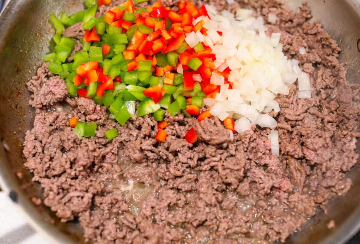 Overhead shot of beef, onions and peppers cooking in a skillet. 