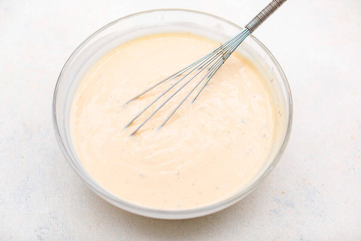 Overhead shot of evaporated milk and the cream of mushroom and chicken soups whisked together in a bowl. 