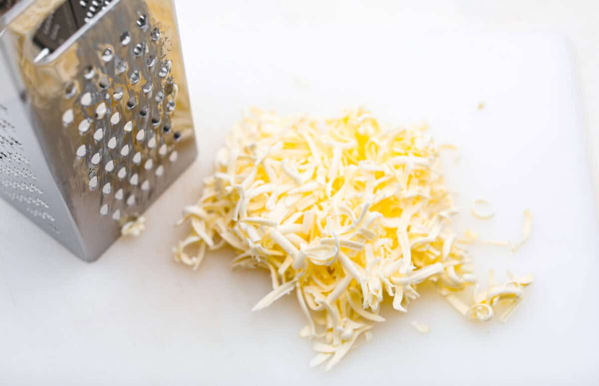 Overhead shot of cold butter grated in a cheese grater. 