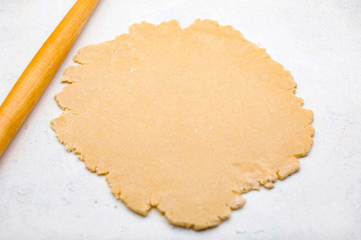 Overhead shot of the pie crust rolled out next to a rolling pin. 